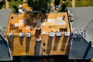 A worker replace shingles on the roof of a home repairing the roof of a home